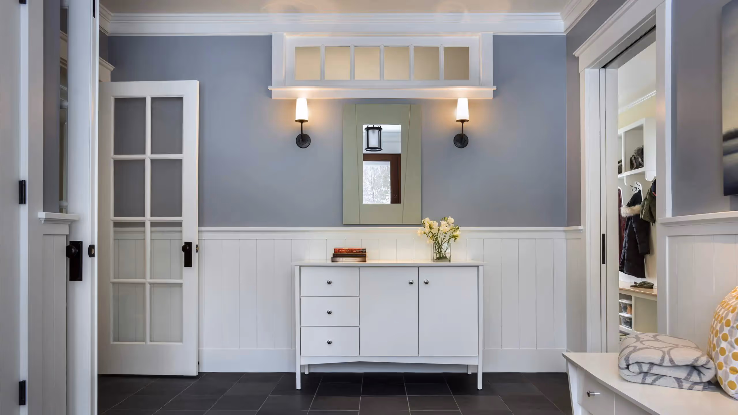 Elegant mudroom with white cabinets, gray walls, and wall sconces