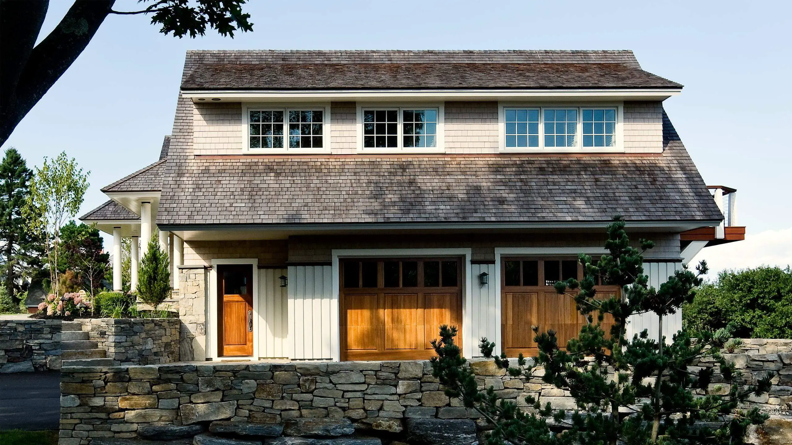 Two-story house with wooden doors, stone walls, and multiple windows