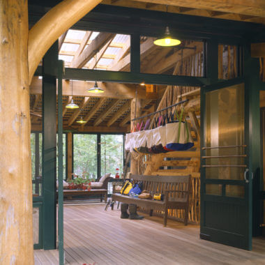 Rustic wooden porch with hanging laundry, bench, and green-framed windows