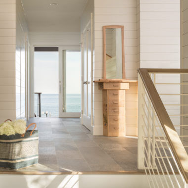 Bright coastal hallway with ocean view, wooden furniture, and natural light