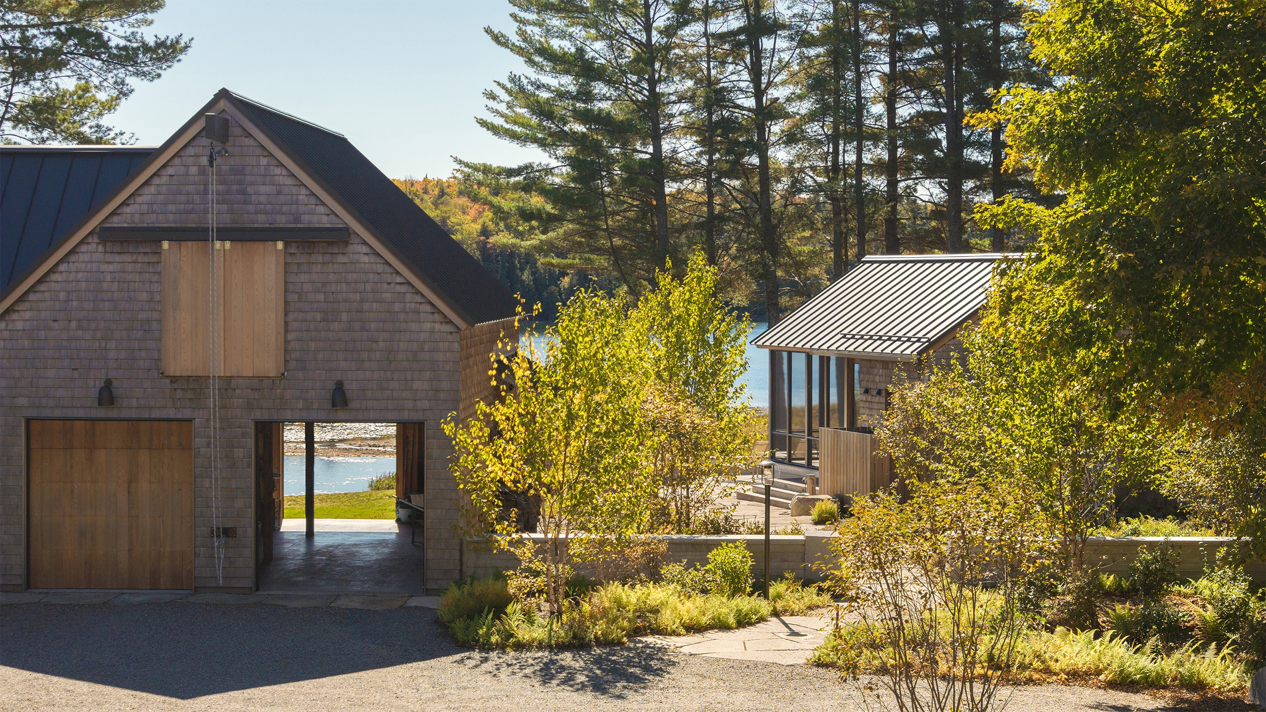 Catalogued architectural features and outdoor design elementsCatalogued architectural features and outdoor design elementsCedar-shingled exterior of Moe's Cove with screened porch, standing-seam metal roof, and outdoor shower, framed by birch trees and ferns on the lakeside lawn.