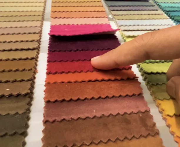 Hand with finger pointing at various shades of fabric swatches in a color palette.