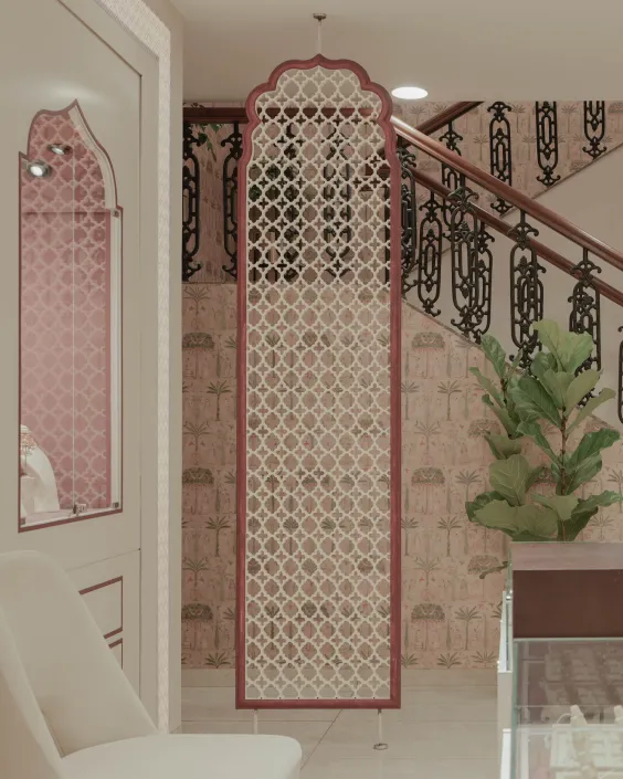 Tall decorative room divider with geometric patterns in a stylish interior near staircase and plant.