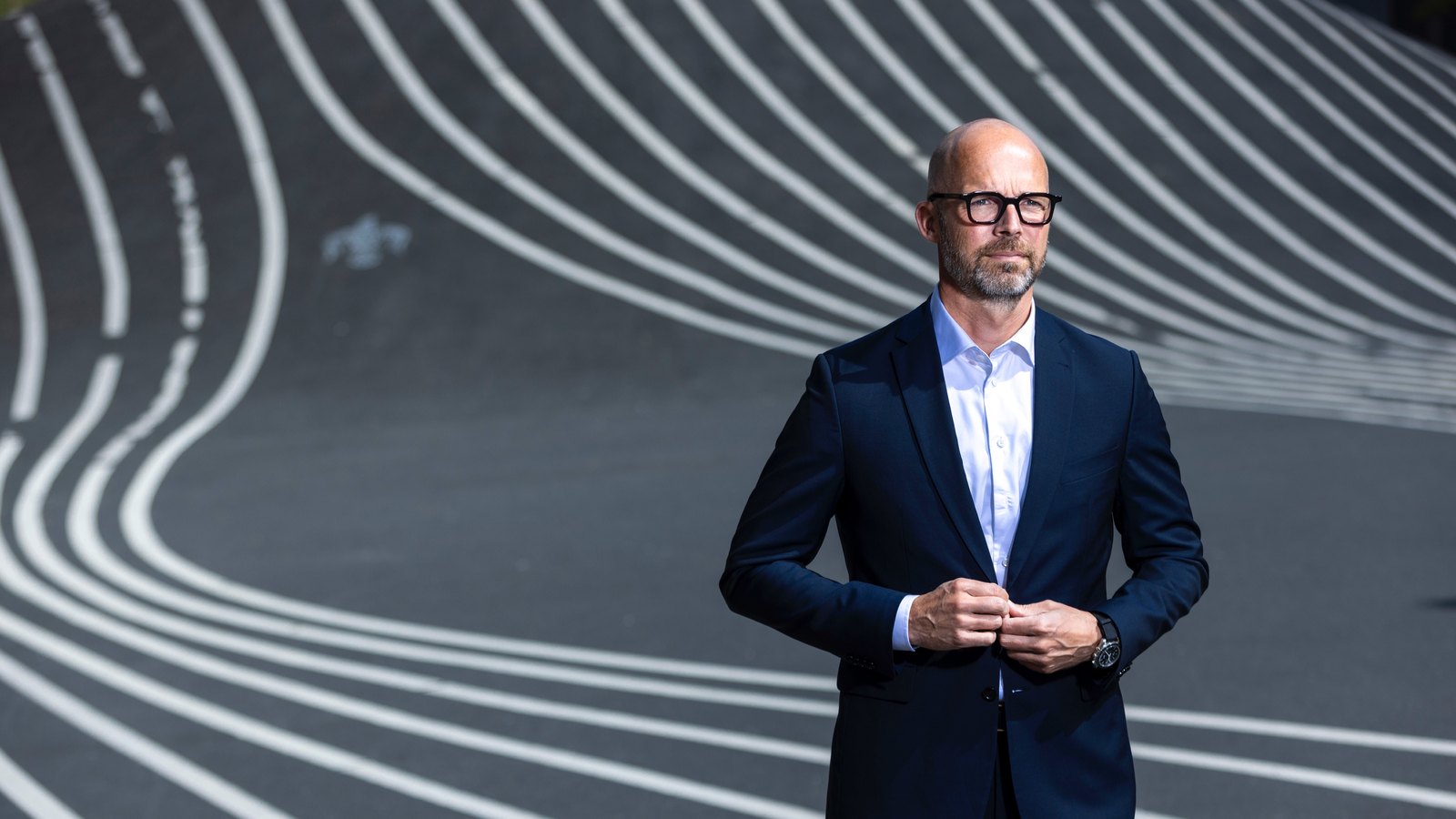 Peter Sorgenfrei standing in a suit on a curved graphic surface