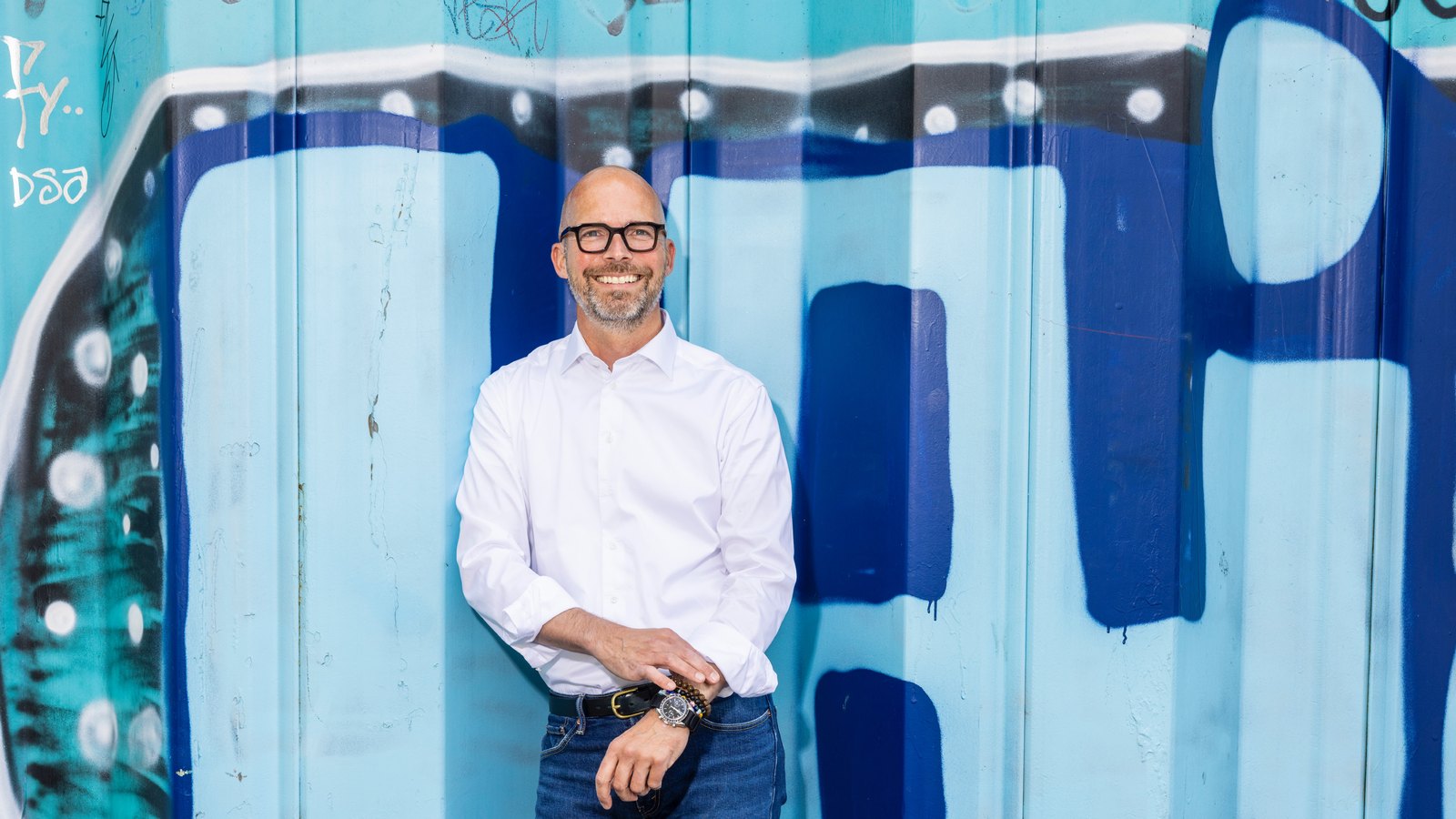 Peter Sorgenfrei leaning against a blue painted wall