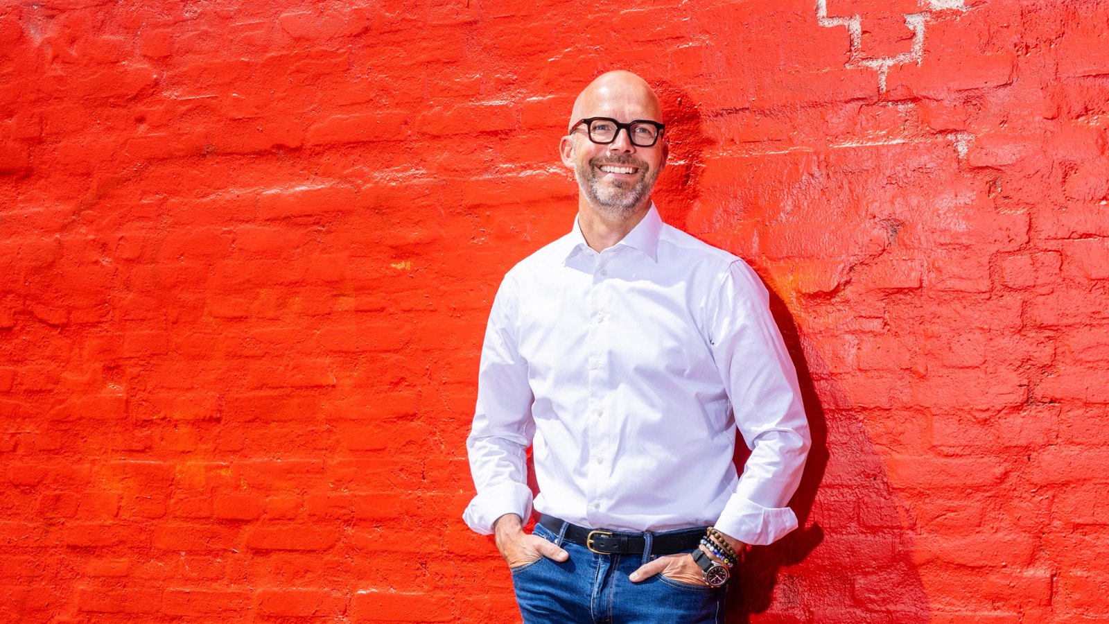 Peter Sorgenfrei leaning against a red wall