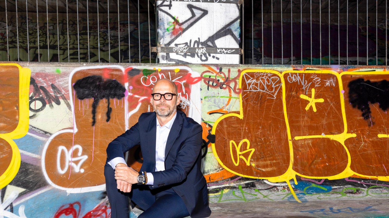 Peter Sorgenfrei seated against a graffiti wall