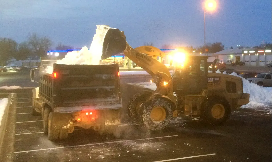 Loading dump truck with snow at night