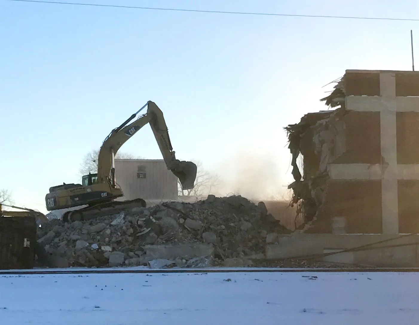 Excavator tearing down brick building