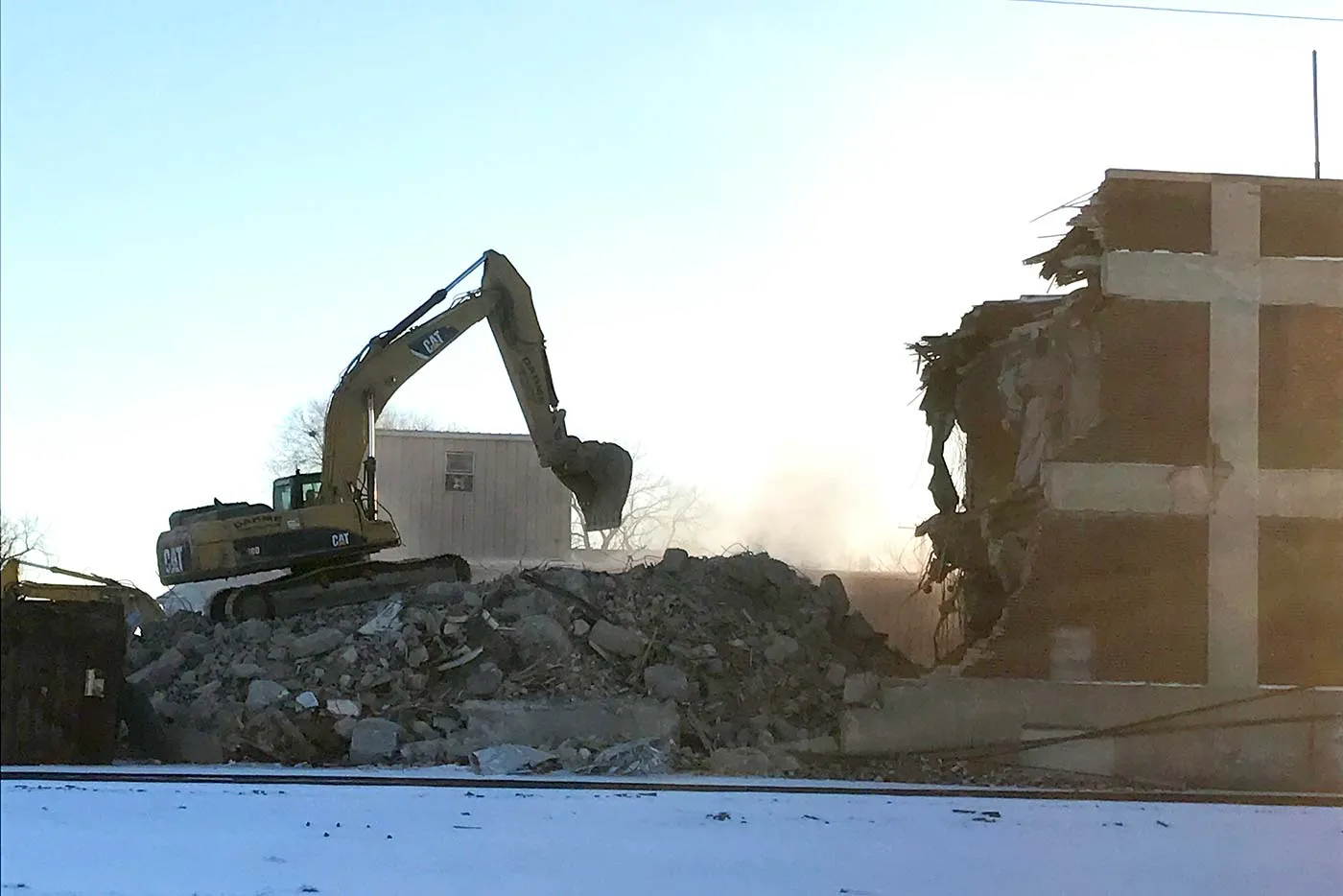 Excavator tearing down brick building