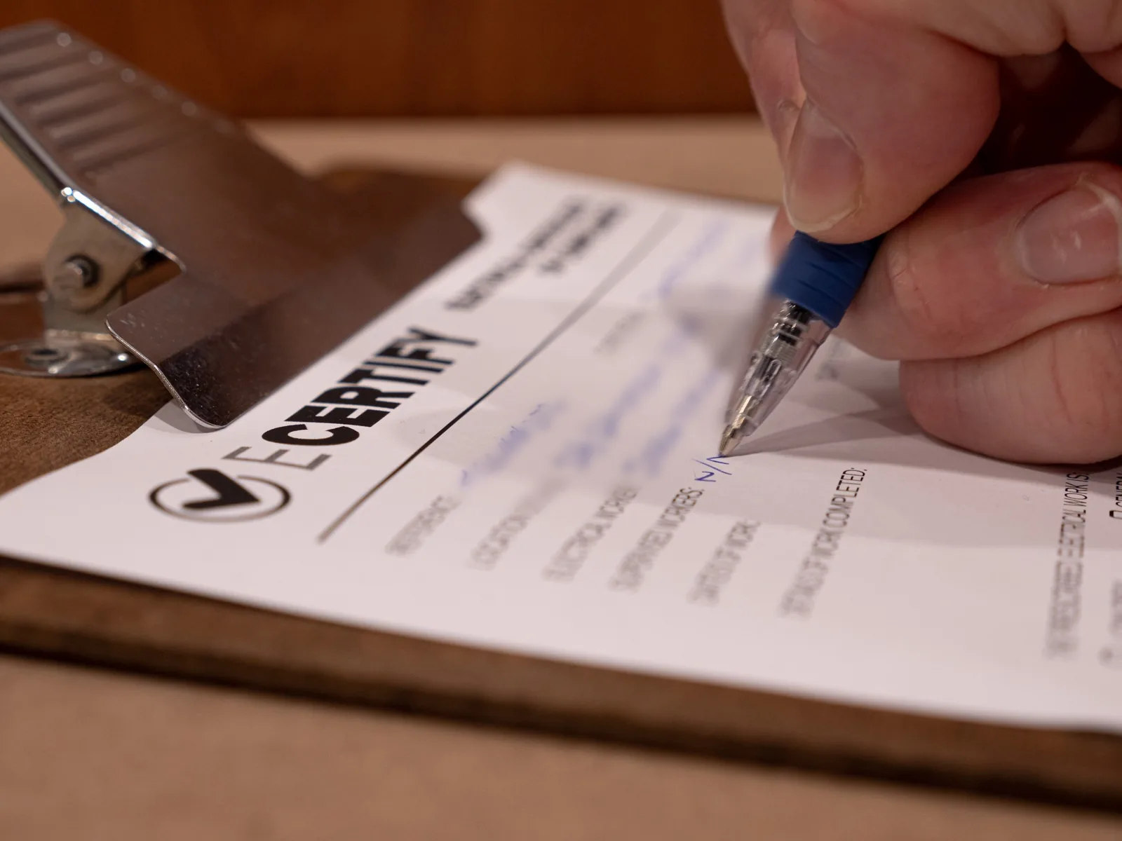 Electrician signing an electrical certificate on a clipboard