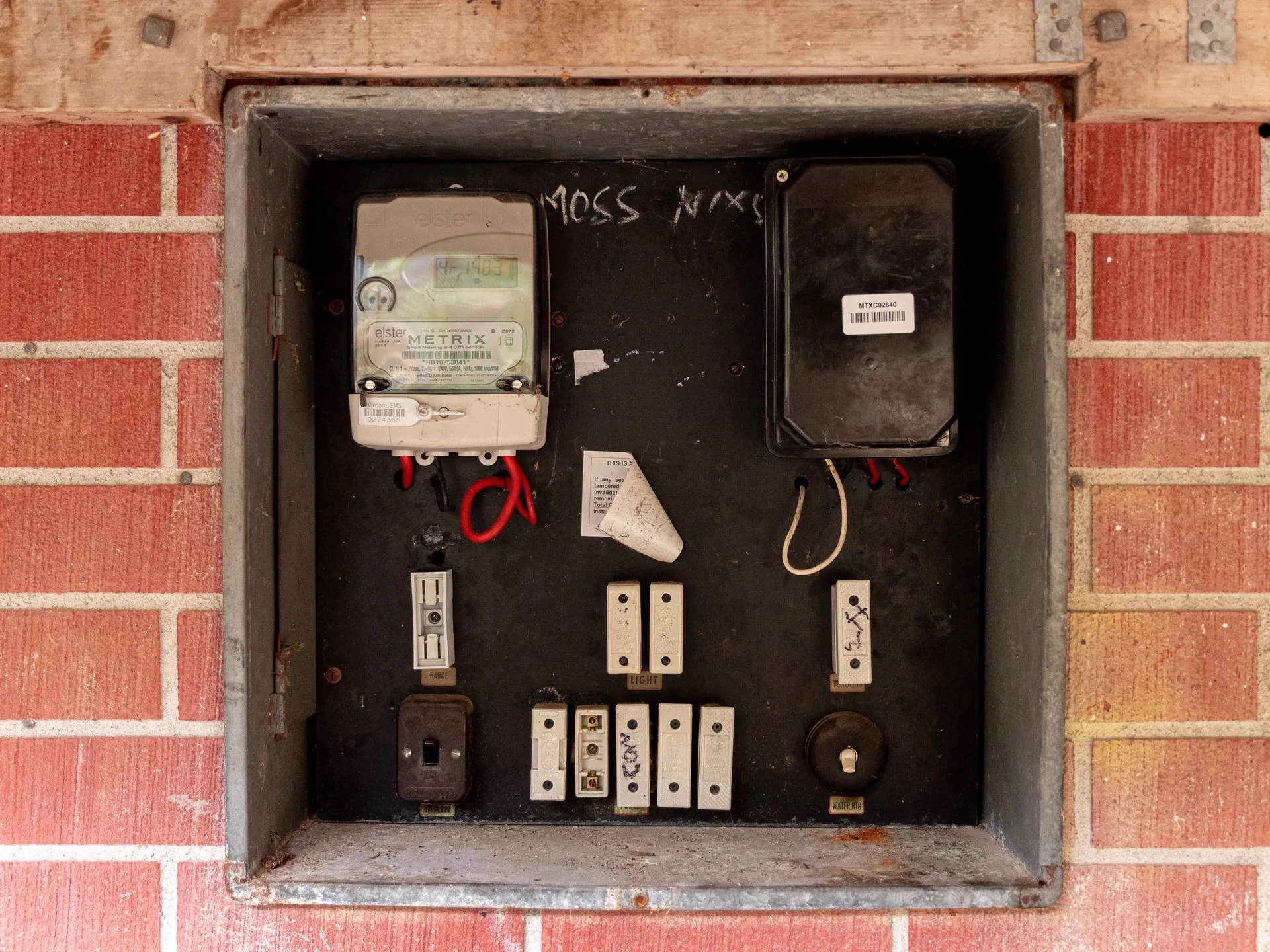 An old ceramic fuse switchboard set into the brick wall of a house