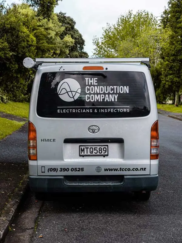The back of a branded Conduction Company van parked on a tree-lined driveway