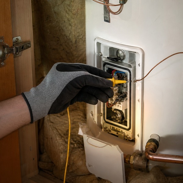 Electrician testing a hot water cylinder thermostat with a multimeter