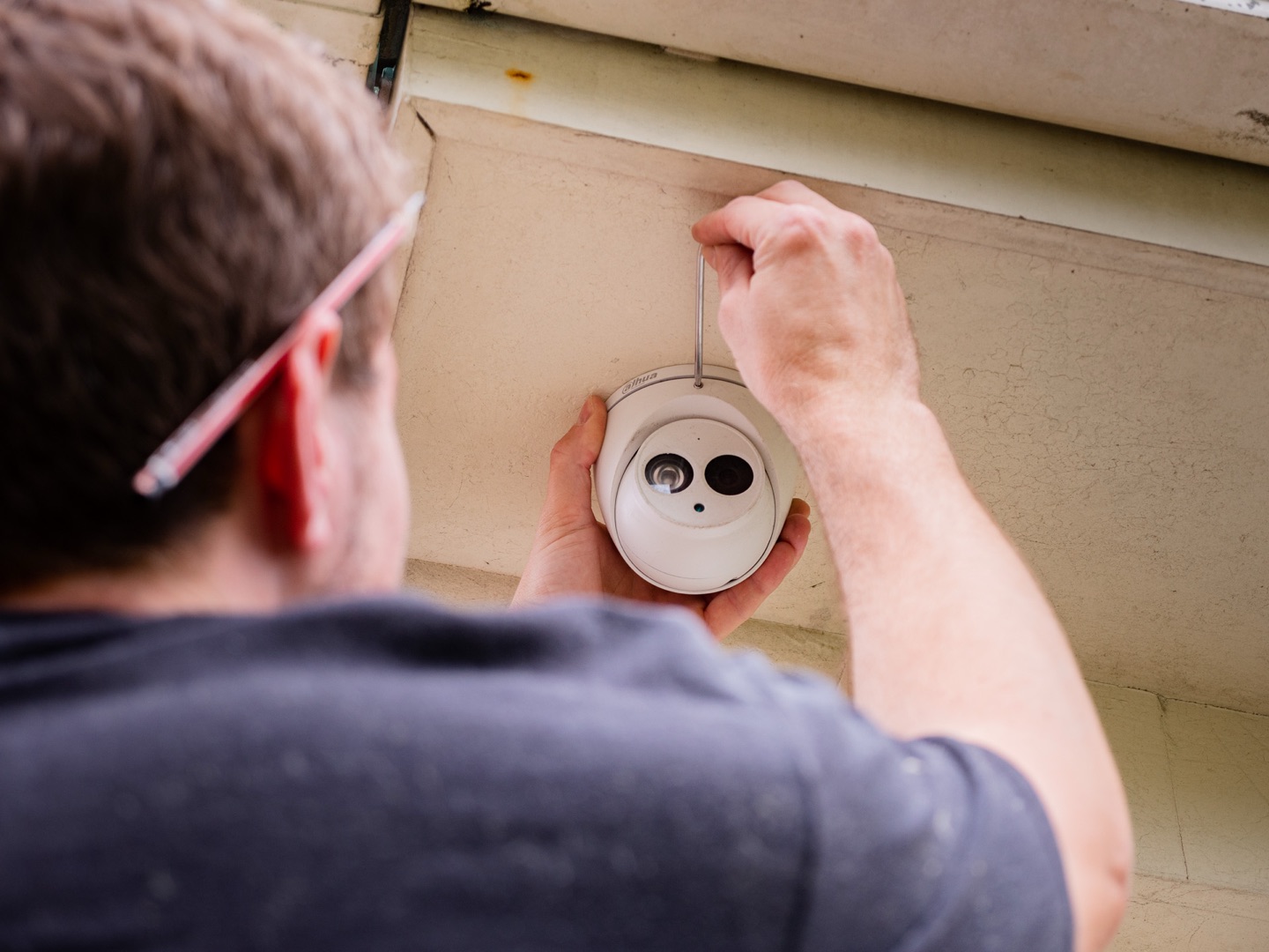 TCCO electrician installing a dome CCTV camera under the eaves of an Auckland home