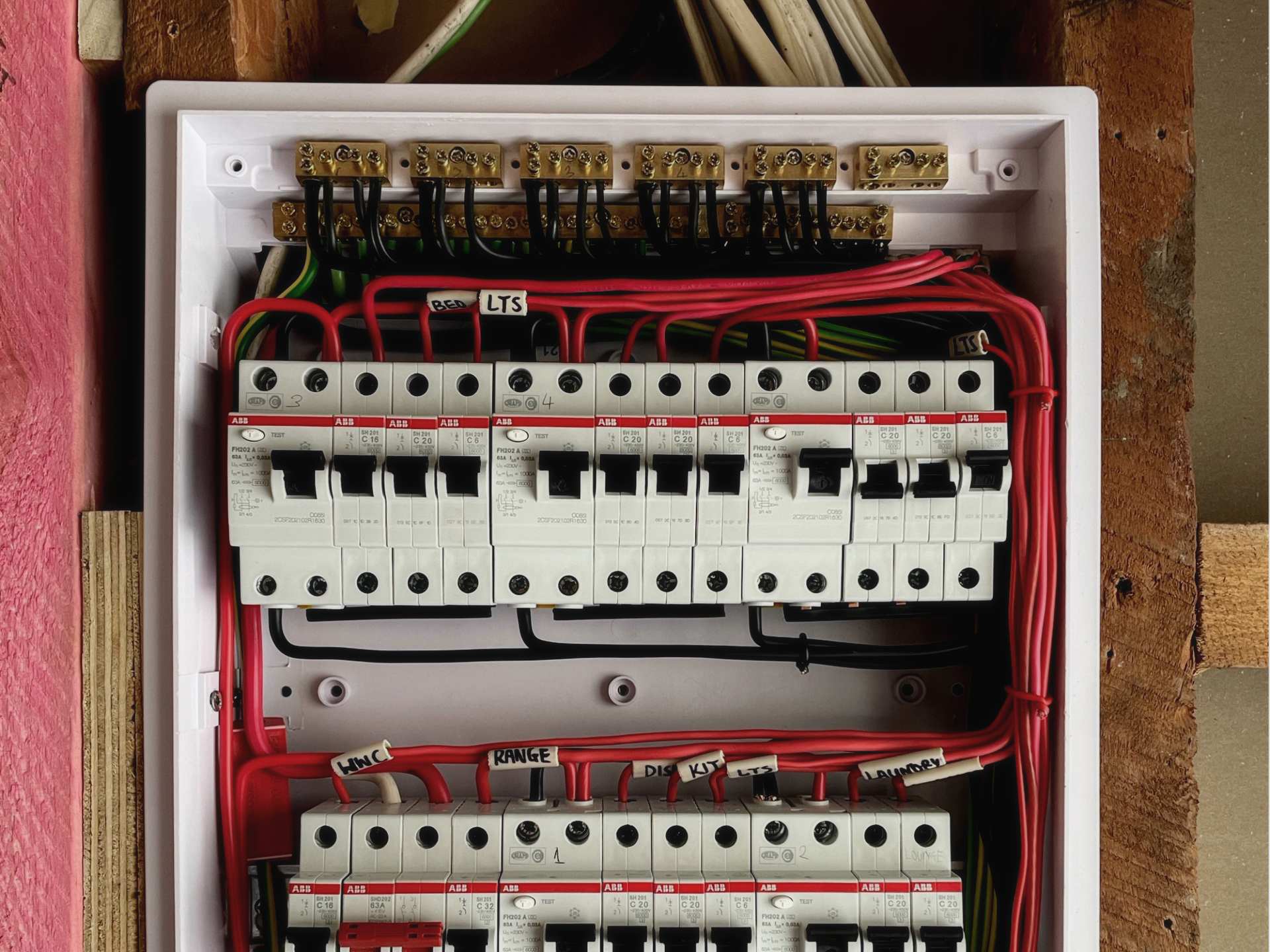 An open modern switchboard with two rows of circuit breakers and red wiring