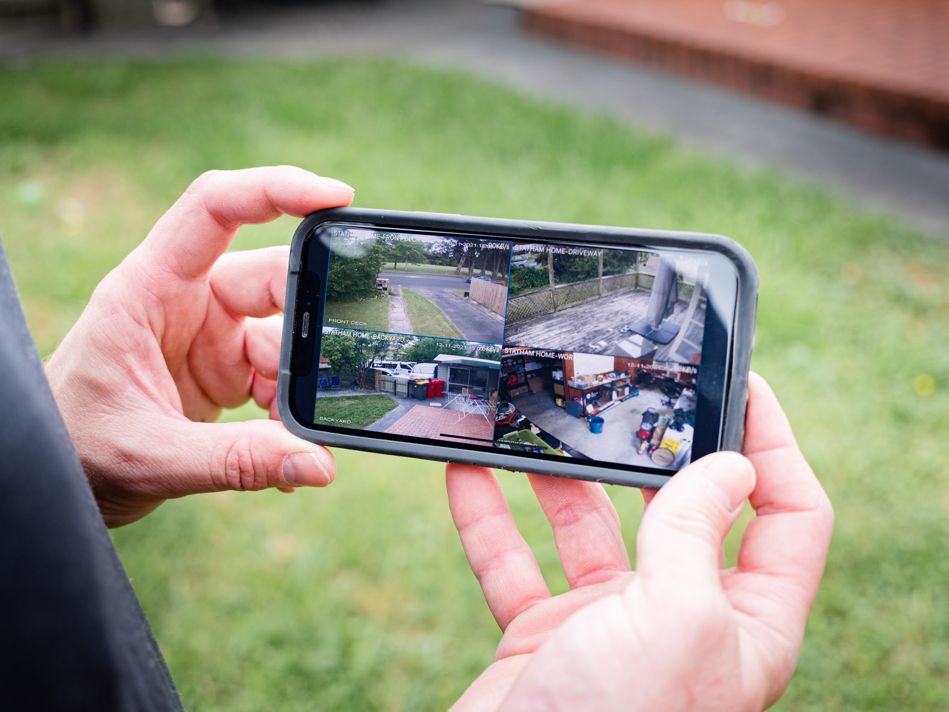 Hands holding a phone showing several live CCTV camera feeds