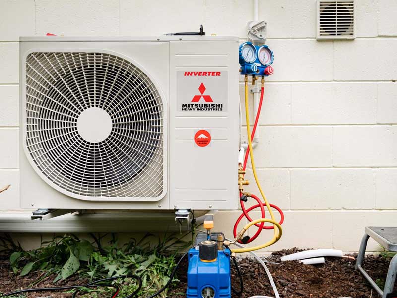 An outdoor heat pump unit connected to refrigerant gauges and a vacuum pump