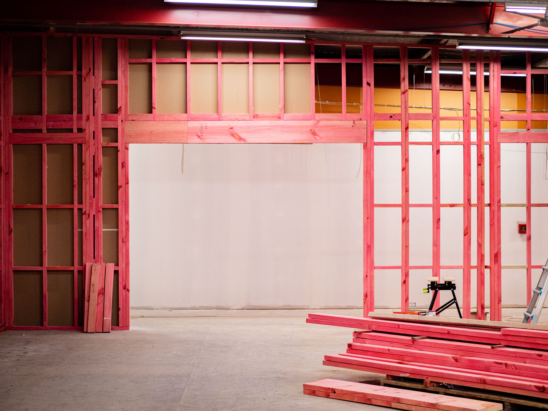 Commercial tenancy part way through a fitout, with steel wall framing erected and steel track stacked on the floor.