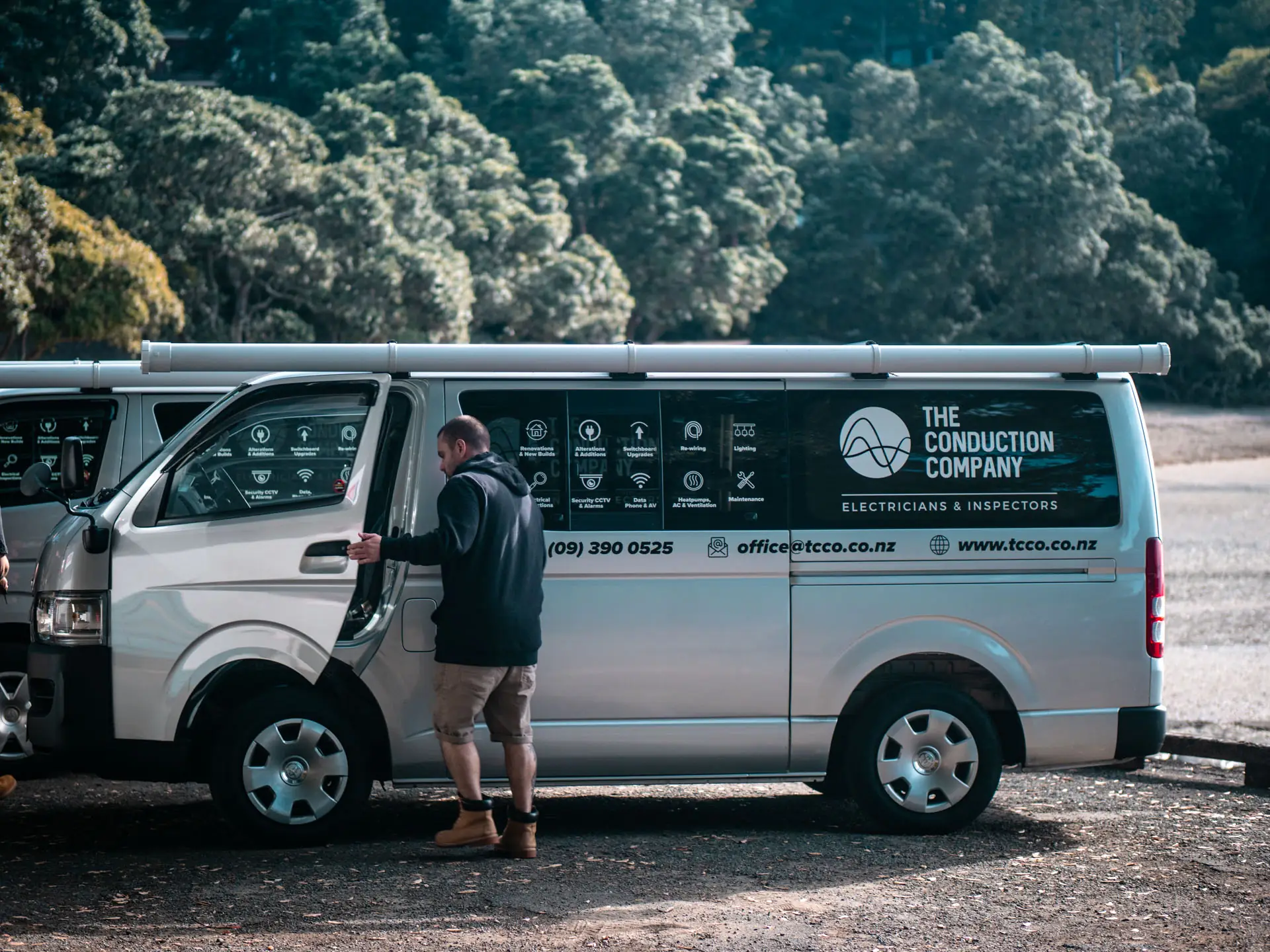 An electrician climbing into a signwritten The Conduction Company van, heading out to a job in Auckland