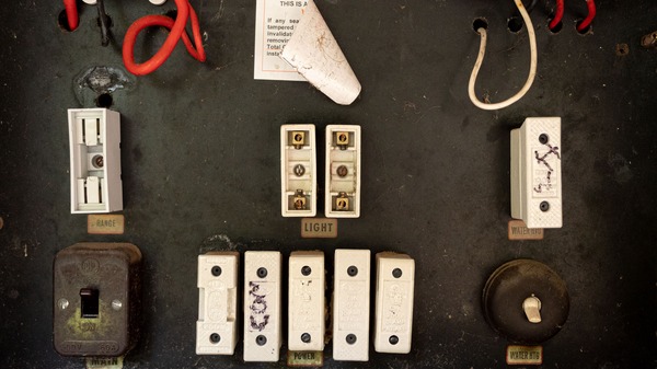 An older Auckland home's original ceramic fuse switchboard with its main switch and fuse carriers