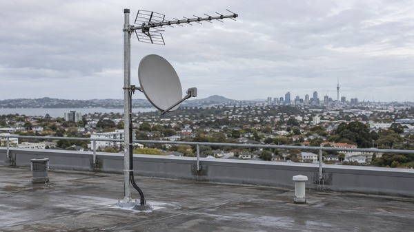 A shared TV aerial and satellite dish mounted on the roof of an Auckland apartment building