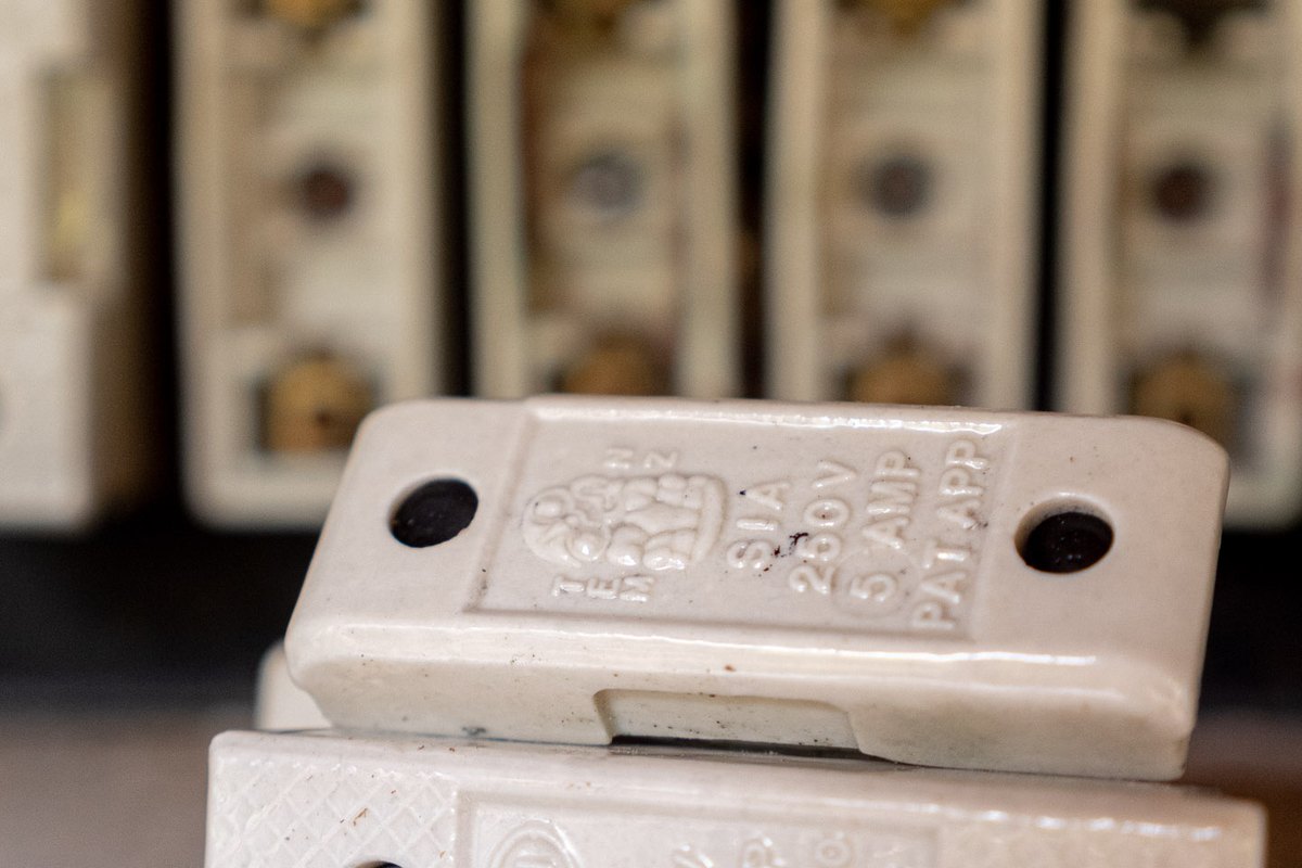 Close-up of a ceramic fuse carrier with 5 AMP 250V embossed in the porcelain, old fuse ways behind.