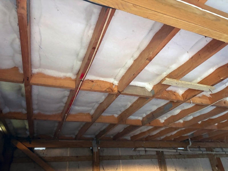 White insulation blanket fitted between the timber joists under a house floor