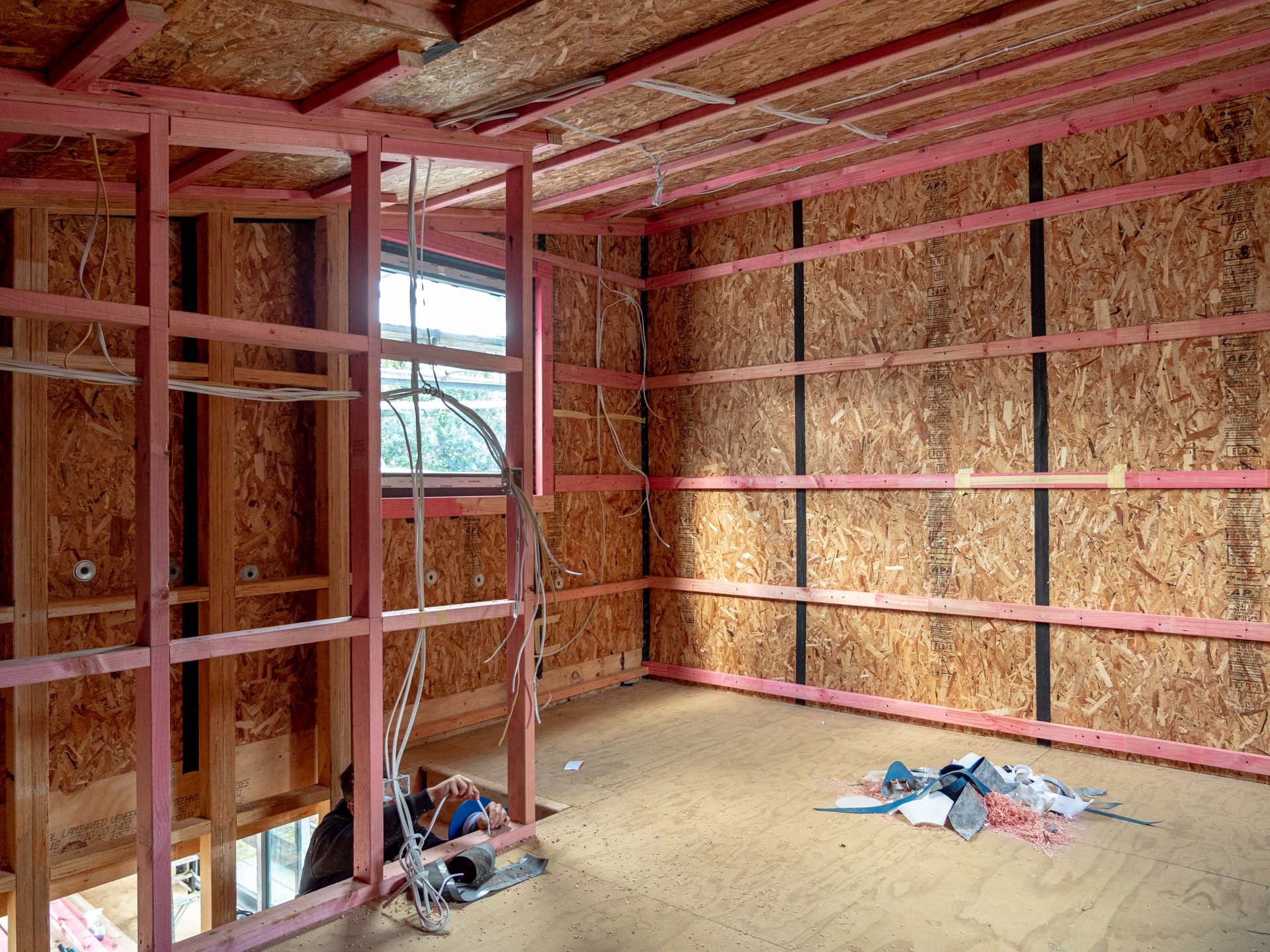 A framed room in a new build with wiring run through the timber studs before the walls are lined