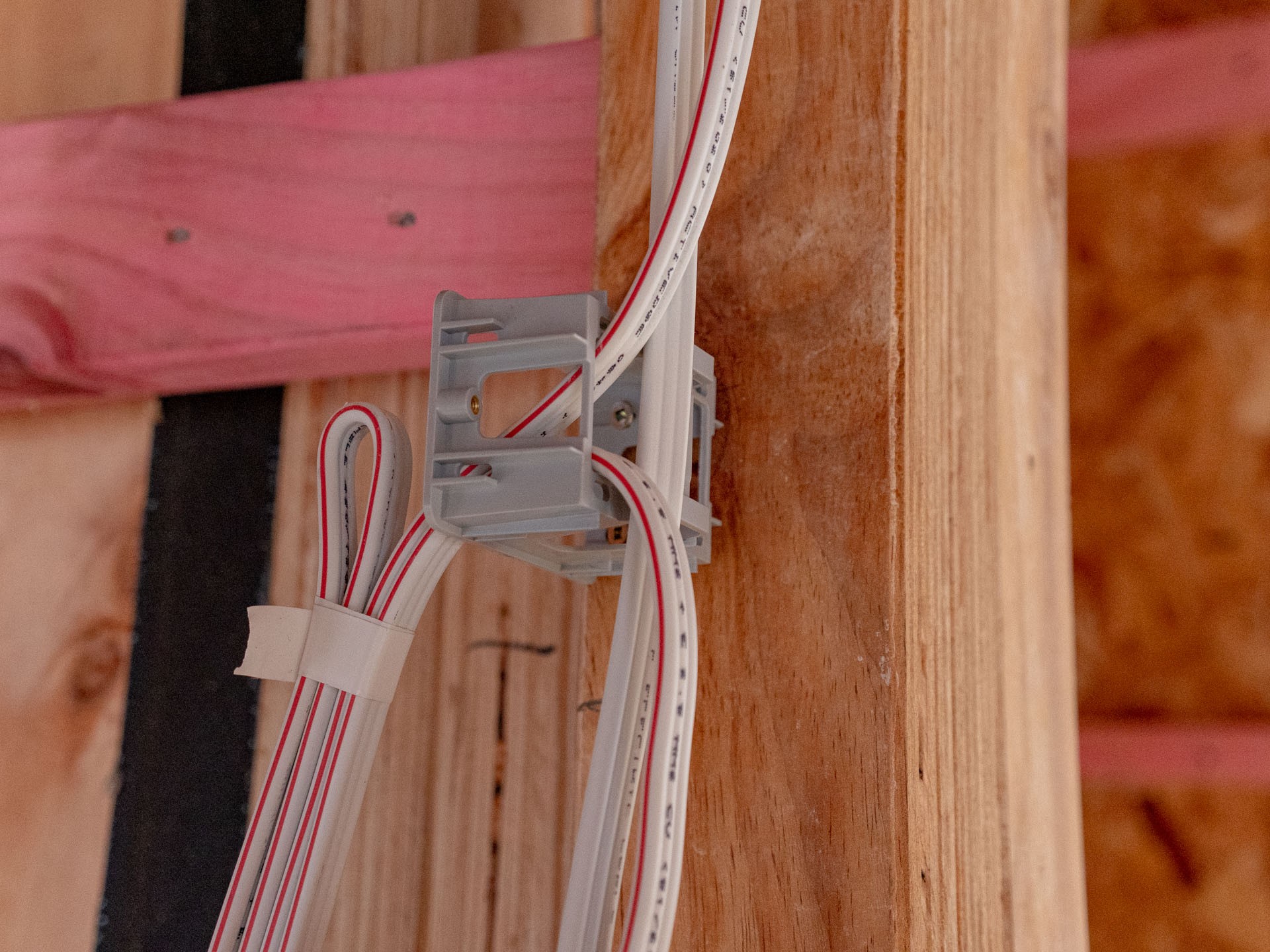 Flat cables running into a flush box mounted on a timber stud in a framed wall