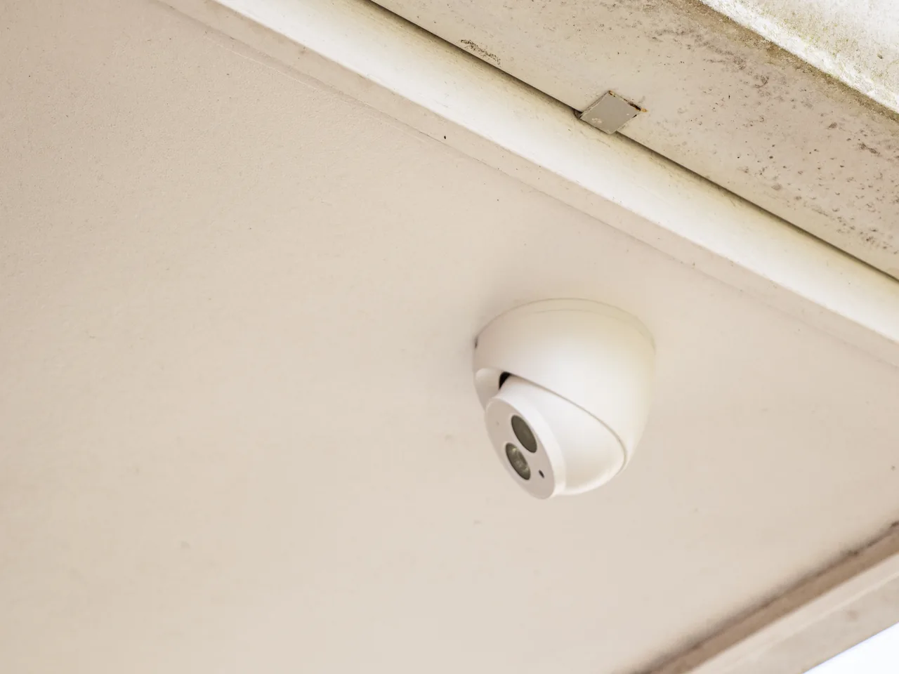 White dome security camera mounted in the soffit of a house