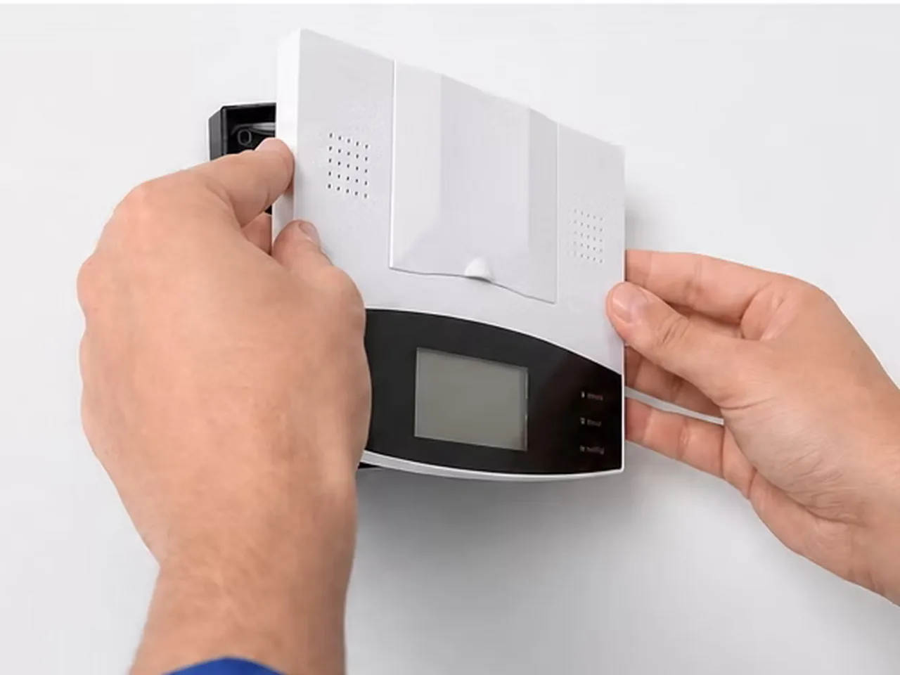 Hands fitting the front of an underfloor heating thermostat onto its wall box