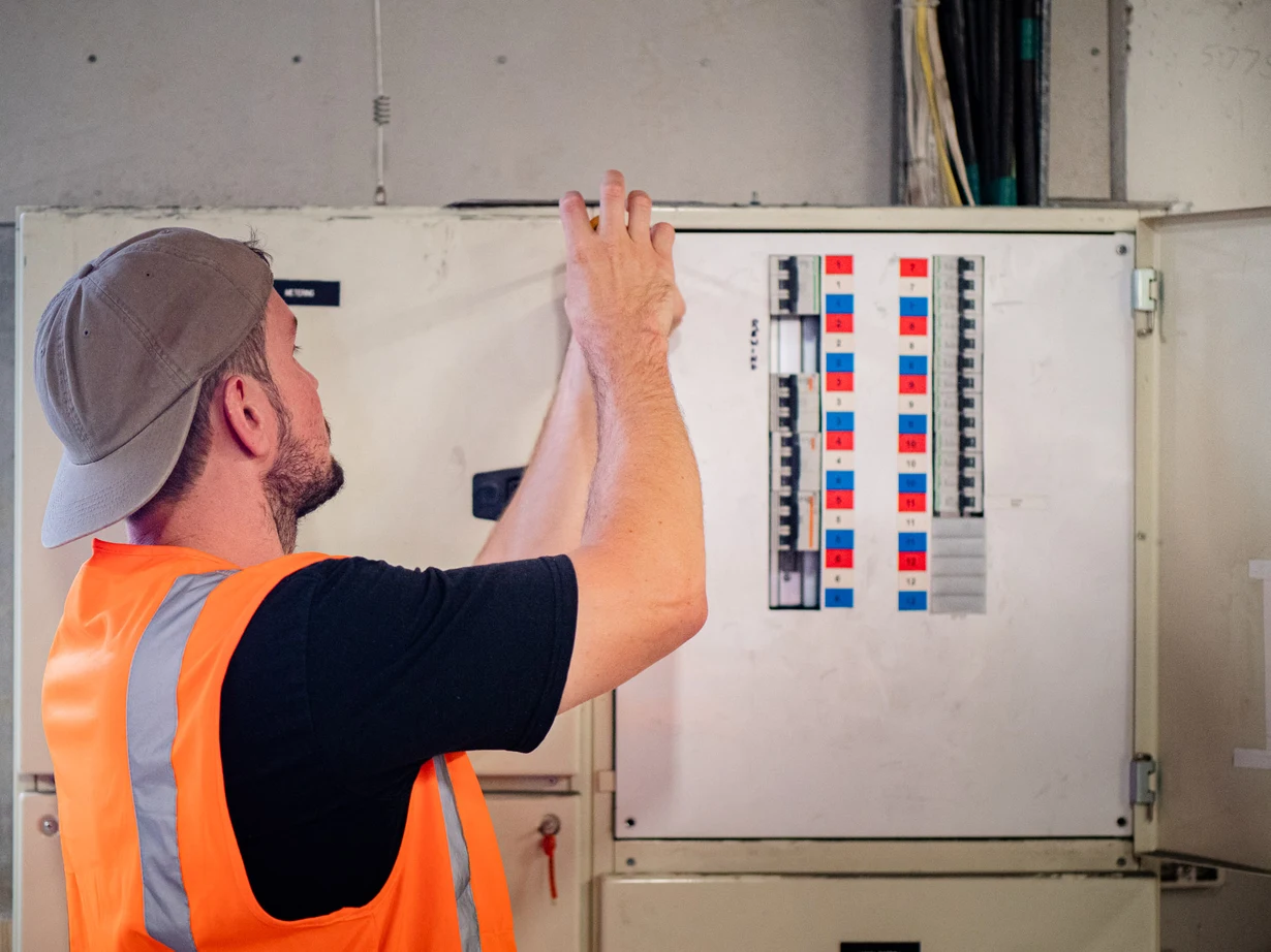 Electrician working inside an open commercial switchboard