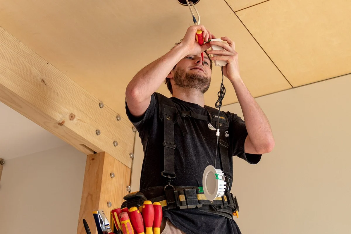 Holding a light fitting up to a ceiling cut-out, ready to fix it in place.