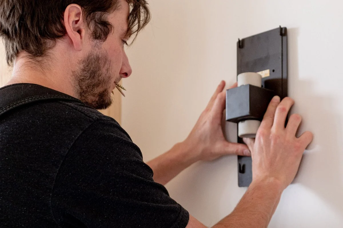 Pressing a wall fitting into place on a wall with both hands.