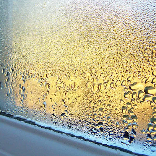 Heavy condensation running down the inside of a window pane onto the sill