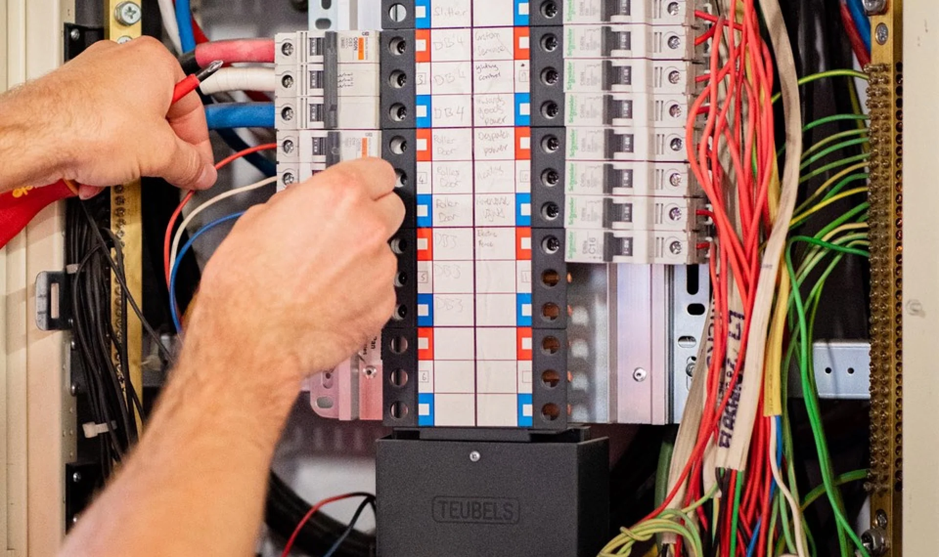 Hands resetting a breaker on a switchboard with hand-written circuit labels