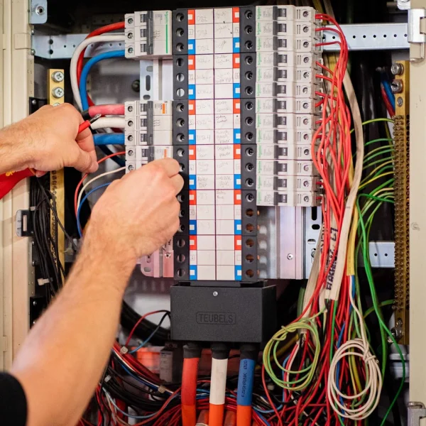 Hands resetting a breaker on a switchboard with hand-written circuit labels