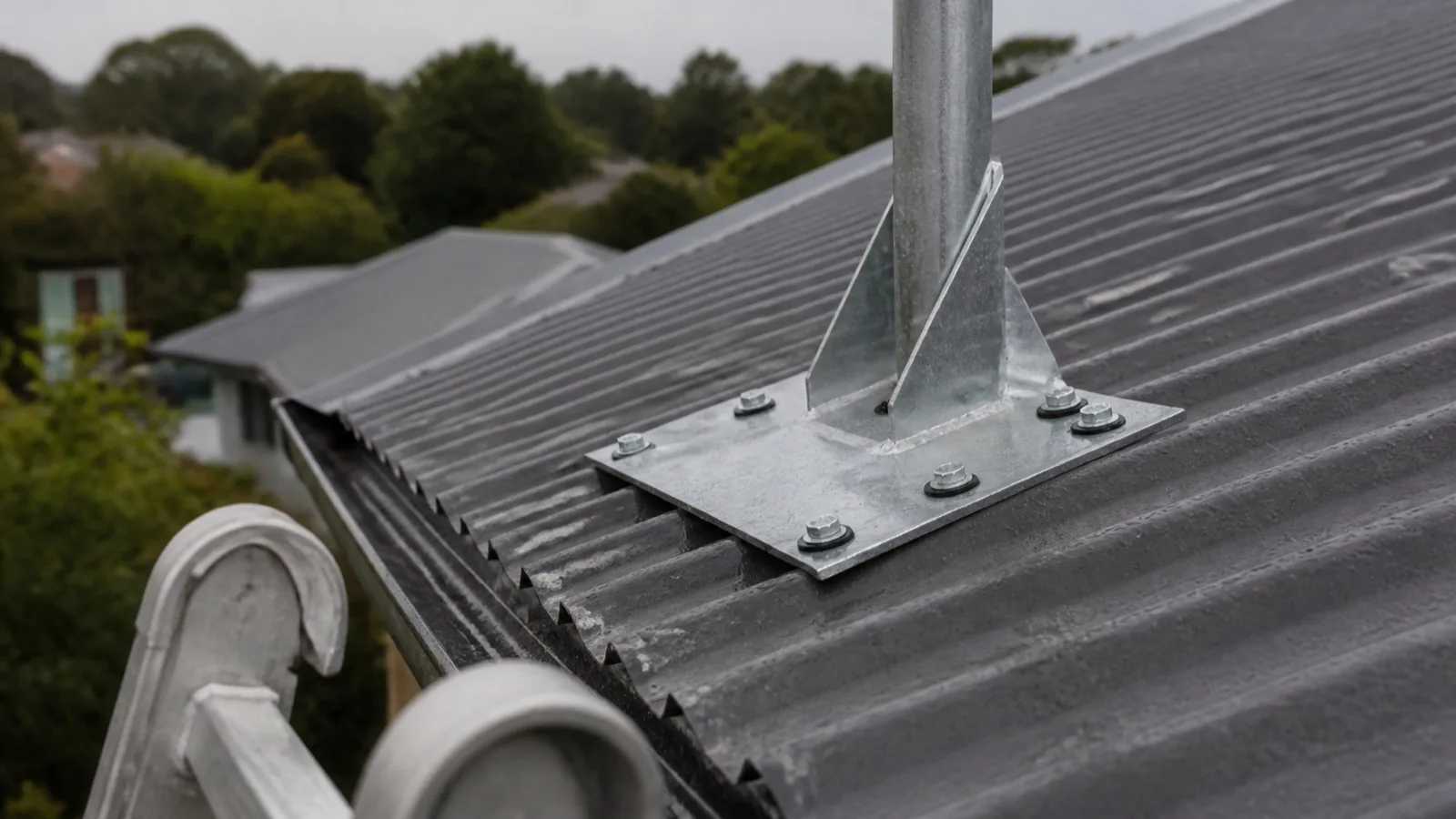 A galvanised aerial mast bolted to a base plate on a corrugated metal roof