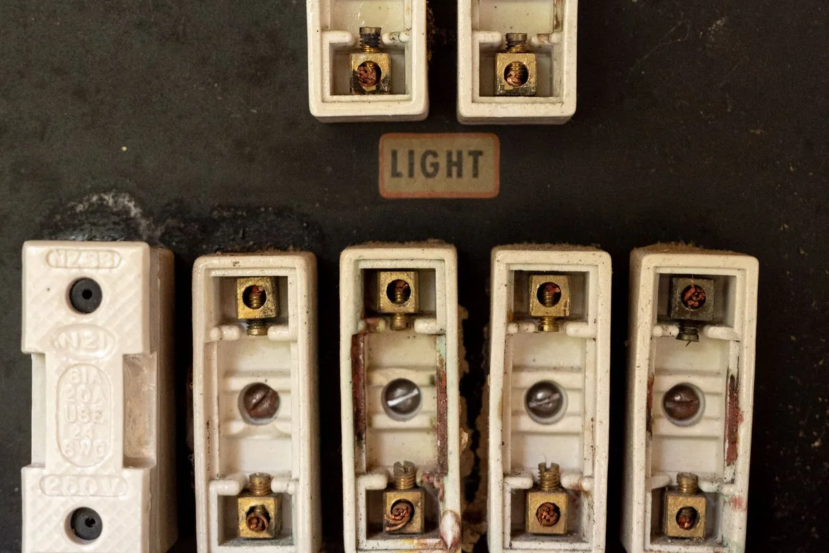 The face of an old fuse board, with porcelain fuse carriers above brass LIGHT and POWER labels.