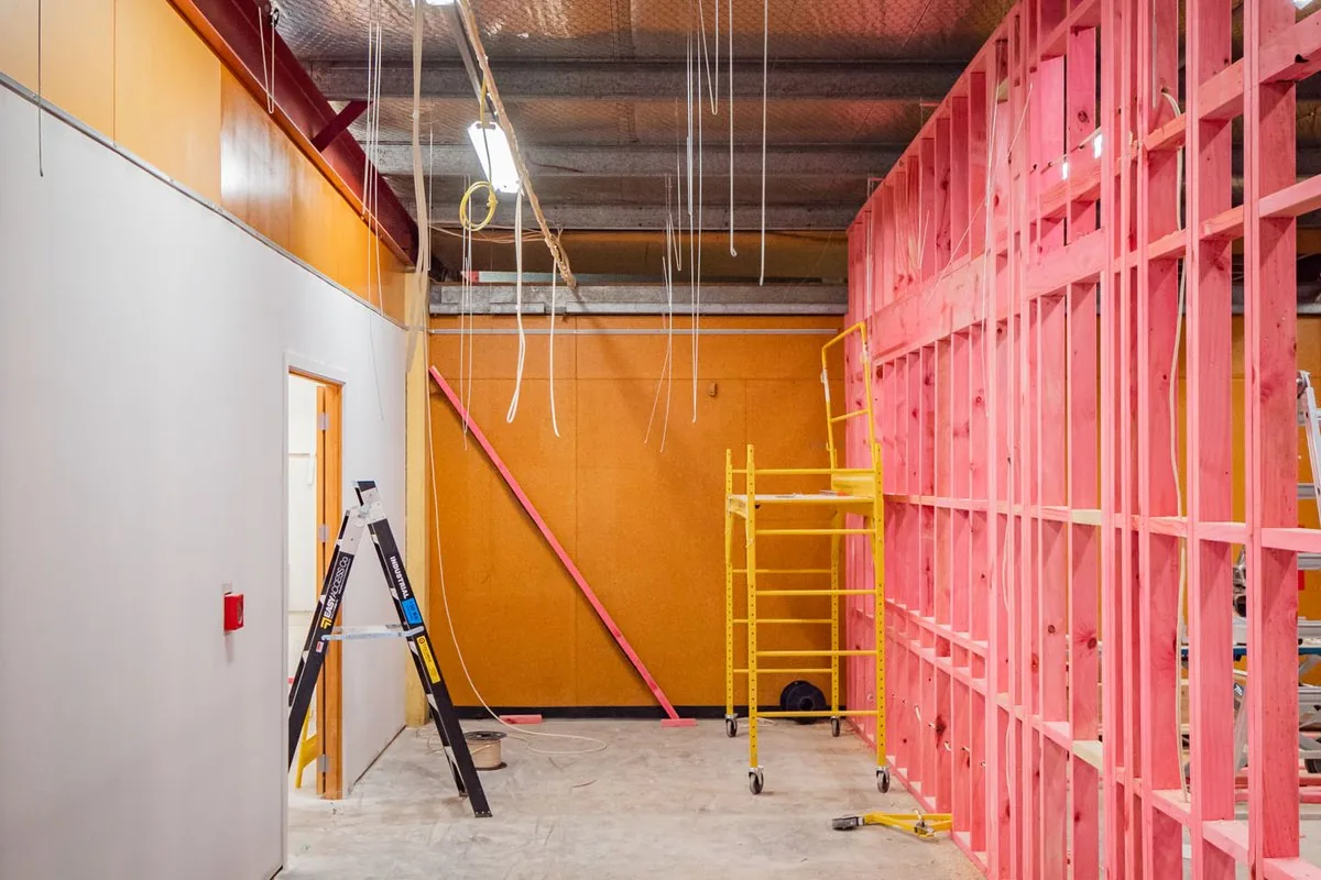 A commercial fit-out in progress, with steel wall framing and cabling dropped from an exposed roof.