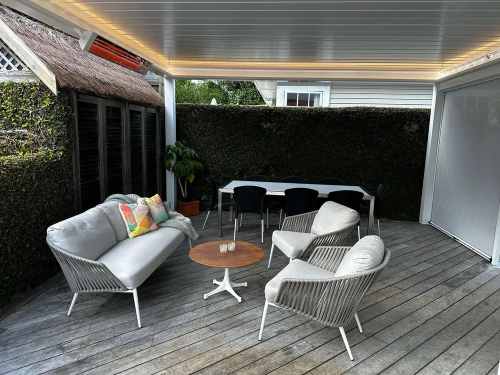 Heaters glowing under a louvre roof above a deck with outdoor lounge chairs