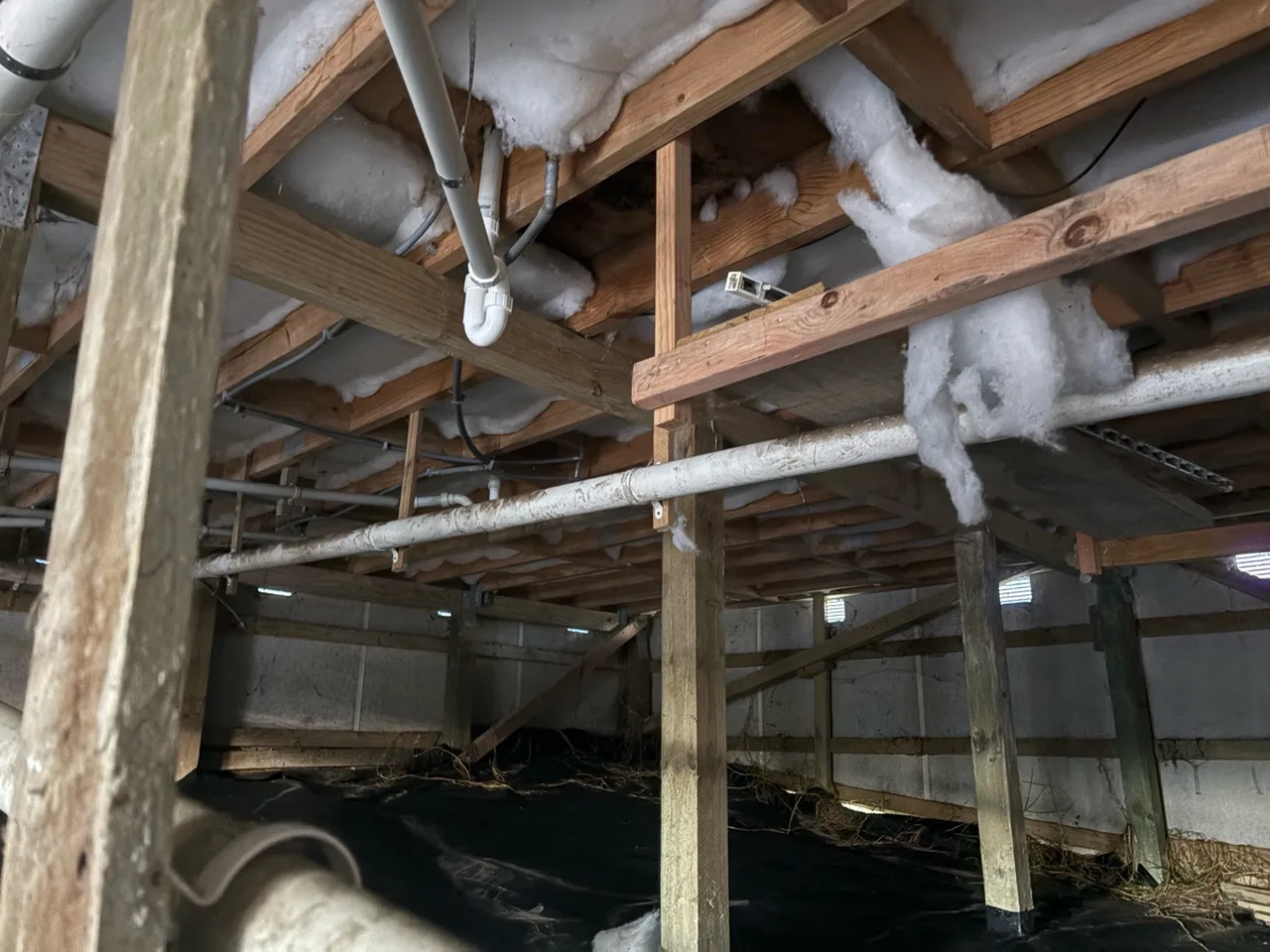 Underfloor space showing insulation, plumbing pipework and timber framing