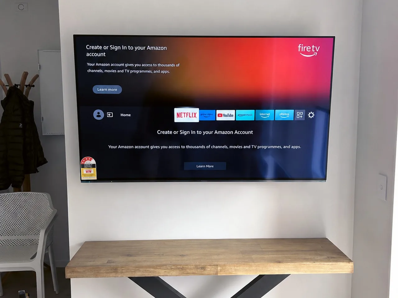 Wall-mounted television on a pivoting arm above a clear wooden desk in a study nook