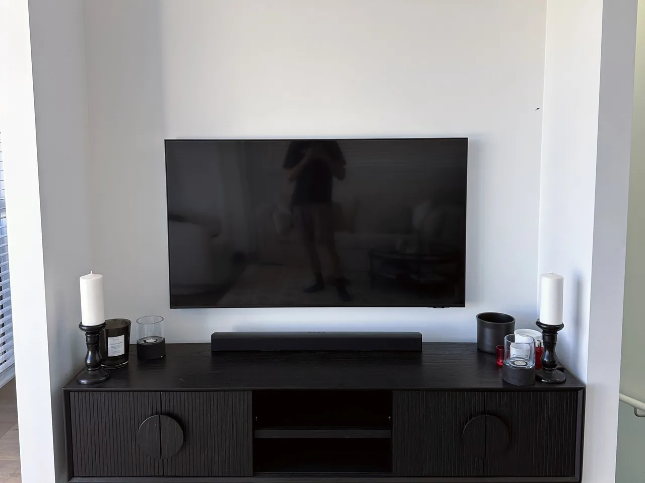 Television in a white wall alcove above a black sideboard with a soundbar