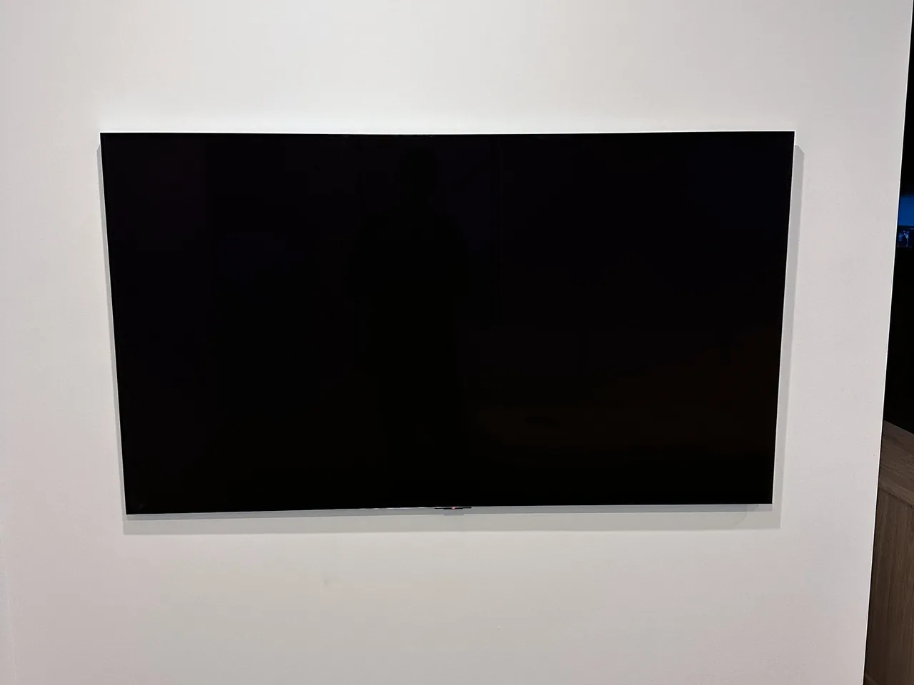 Television mounted flat on a plain white wall, screen off