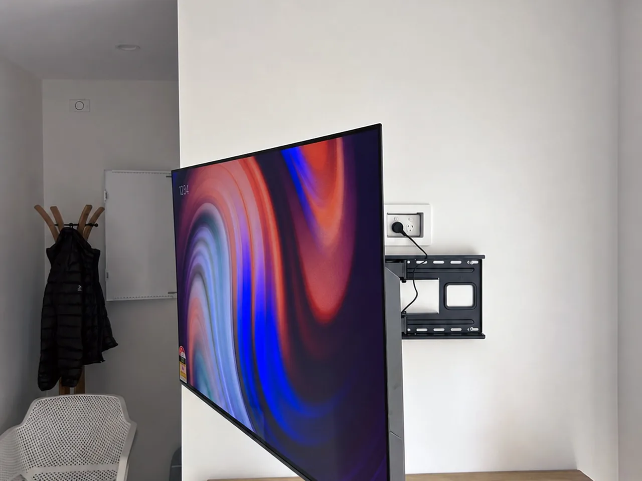Wall-mounted television swung out on its pivot arm, showing the bracket and outlet behind it