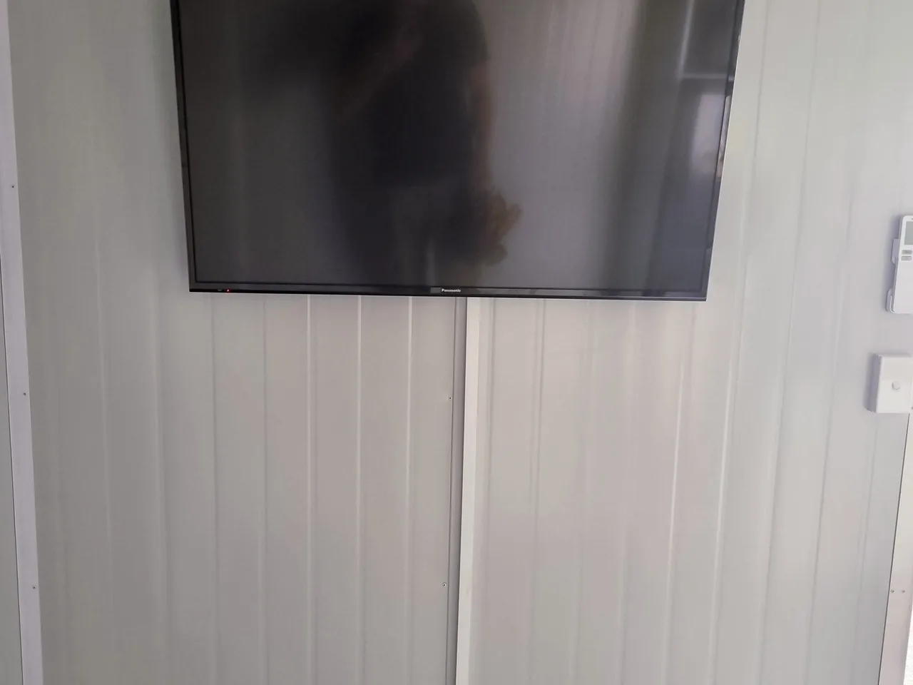 Television on a panelled wall with its cable run down the wall inside a slim white cable cover