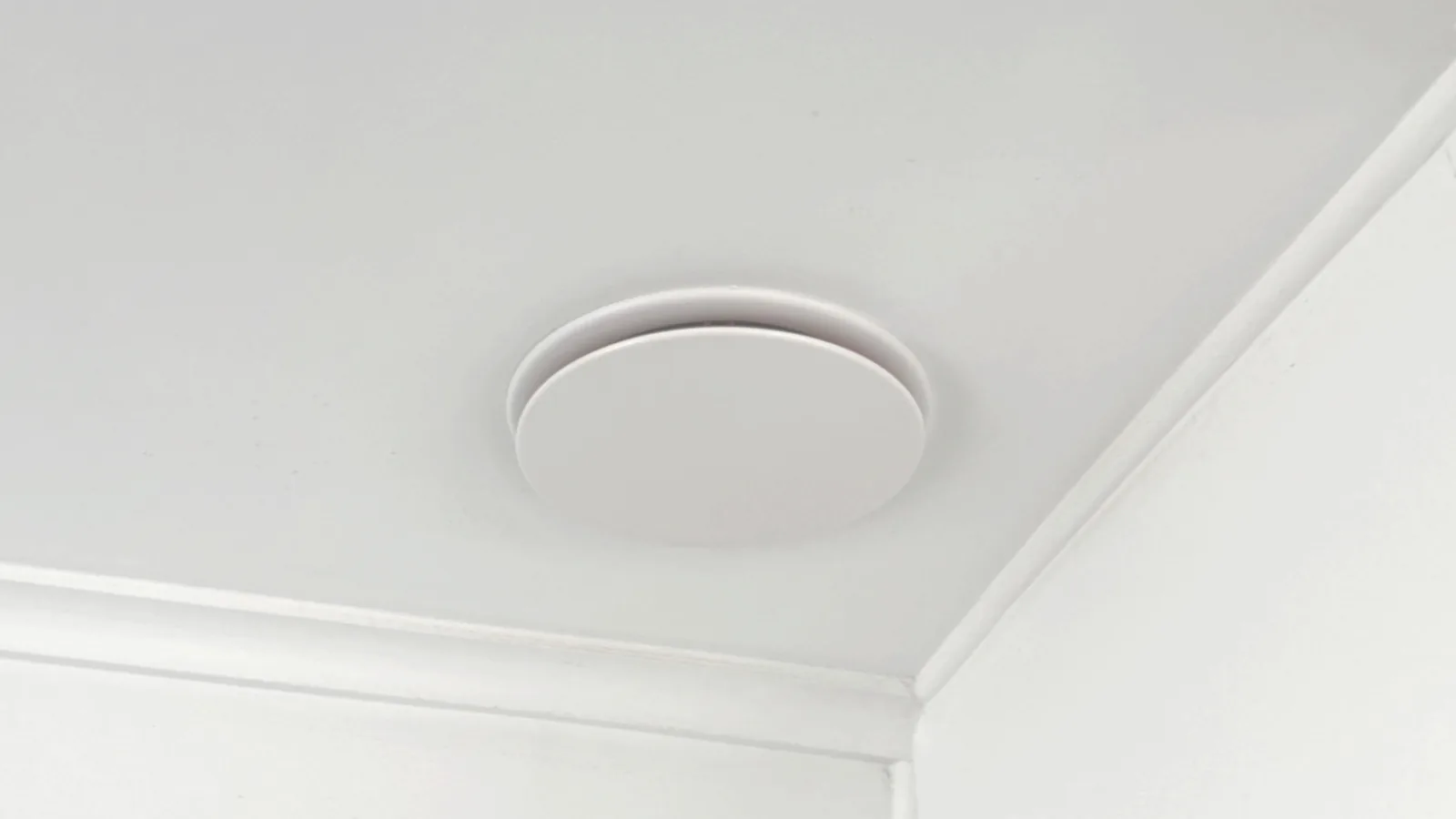 A round white ventilation diffuser set into a ceiling.
