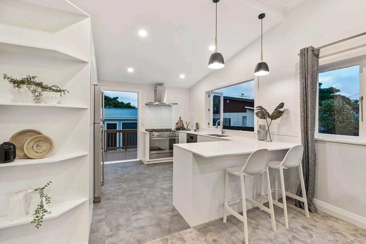 Pendant lights over a kitchen peninsula, with downlights, a canopy rangehood, and an upright cooker